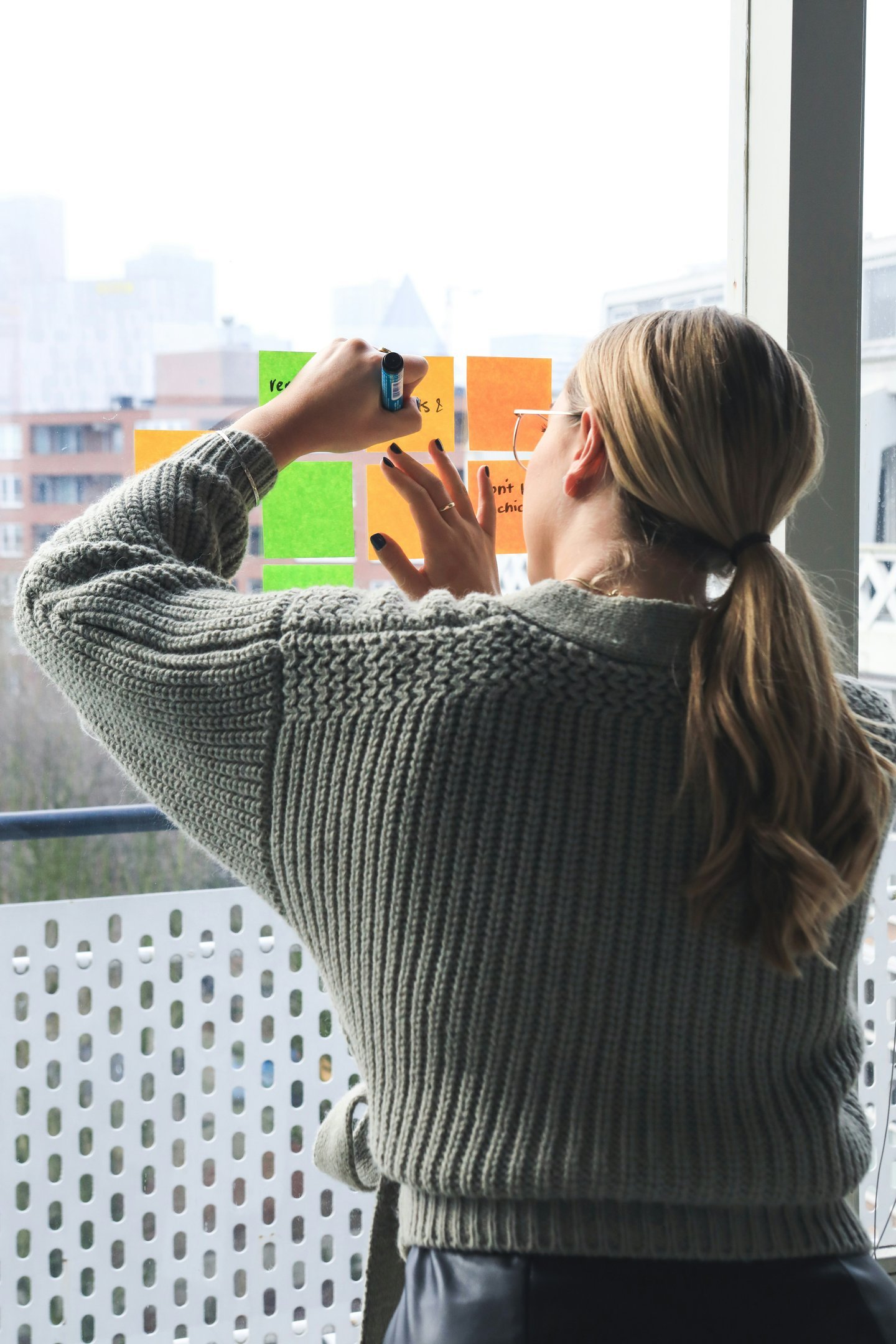 a woman holding a cell phone and taking a picture of a post it notes on